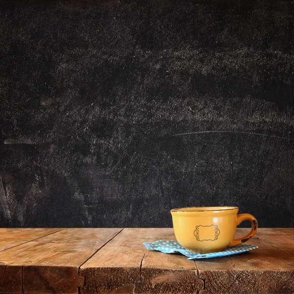Imagen frontal de la taza de café sobre la mesa de madera y las hojas de otoño en frente y el fondo de pizarra con espacio para el texto . —  Fotos de Stock