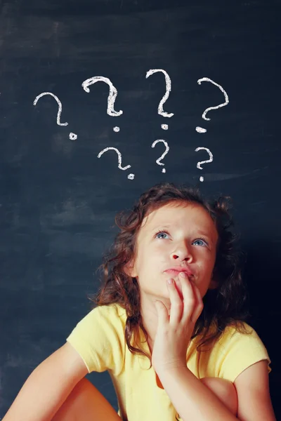 Qute kid next to chalkbord thinking' with  many question marks symbols. — Stock Photo, Image