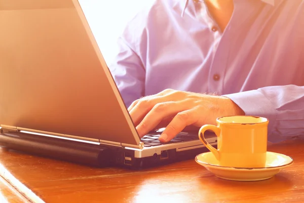 Cerca de la imagen del hombre utilizando el ordenador portátil junto a la taza de café. imagen de estilo retro. enfoque selectivo . —  Fotos de Stock