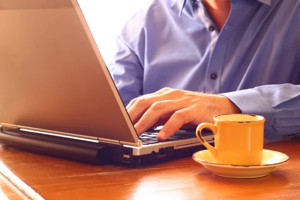 Cerca de la imagen del hombre utilizando el ordenador portátil junto a la taza de café. imagen de estilo retro. enfoque selectivo . —  Fotos de Stock