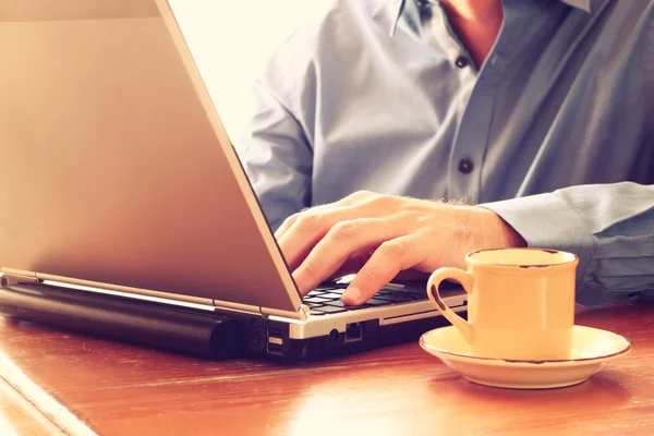 Cerca de la imagen del hombre utilizando el ordenador portátil junto a la taza de café. imagen de estilo retro. enfoque selectivo . —  Fotos de Stock