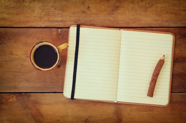 Leeres Notizbuch, altes Papier und Holzstift neben einer Tasse Kaffee über einem Holztisch. Bereit zur Attrappe. — Stockfoto