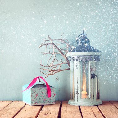 Beyaz ahşap vintage fener mum ve ağaç dalları üzerinde ahşap masa yanma ile. glitter kaplaması ile Retro filtre uygulanmış görüntü.