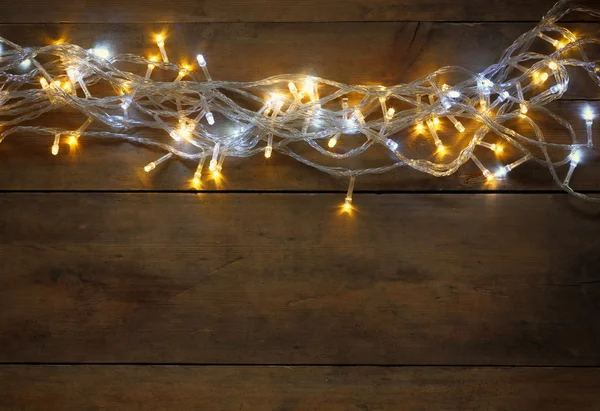 Kerstverlichting warme gouden garland op houten rustieke achtergrond. gefilterde afbeelding. — Stockfoto