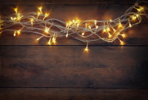 Kerstverlichting warme gouden garland op houten rustieke achtergrond. gefilterde afbeelding. — Stockfoto