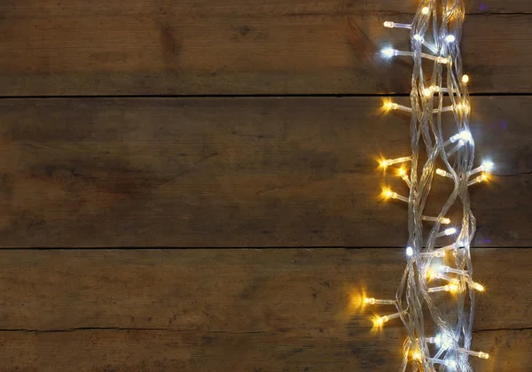 Natal luzes guirlanda de ouro quente no fundo rústico de madeira. imagem filtrada . — Fotografia de Stock