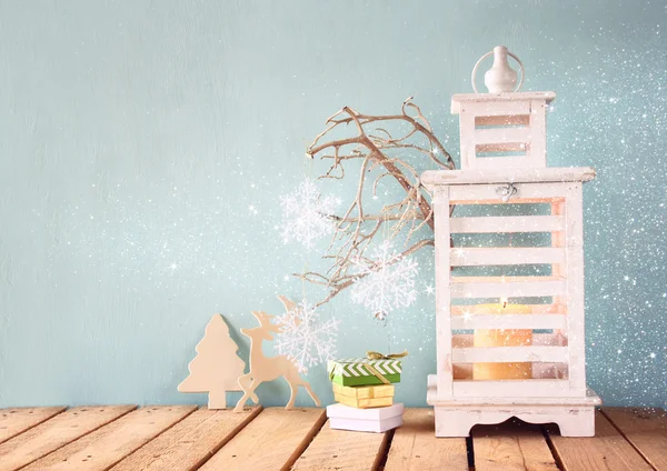 Linterna vintage de madera blanca con vela encendida y ramas de árbol sobre mesa de madera. imagen filtrada retro con superposición de brillo . —  Fotos de Stock