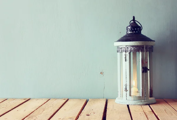 Low key image of white wooden vintage lantern with burning candle and tree branches on wooden table. retro filtered image. — Stock Photo, Image