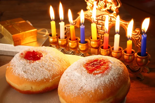 Bild av judiska högtiden Hanukkah menorah (traditionella kandelabrar), munkar och trä dreidels (spinning överst). retro filtrerade bilden. — Stockfoto