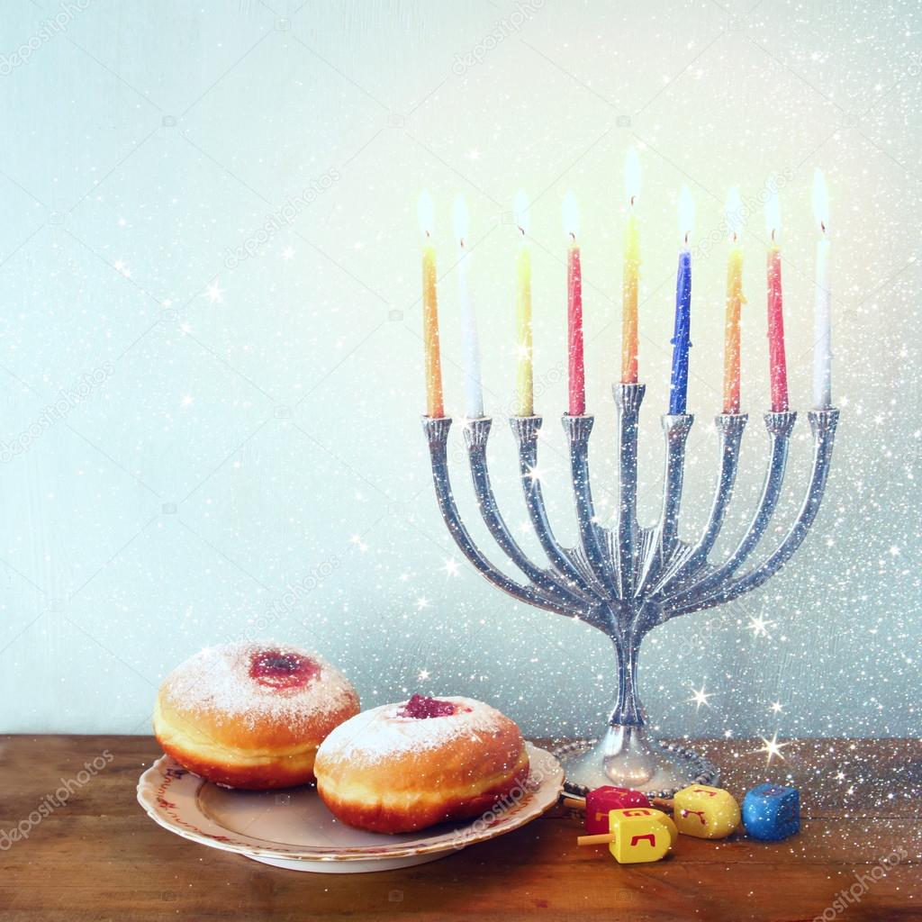 image of jewish holiday Hanukkah with menorah (traditional Candelabra), donuts and wooden dreidels (spinning top). retro filtered image.