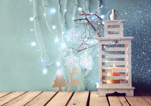 Linterna vintage de madera blanca con vela encendida y ramas de árbol sobre mesa de madera. imagen filtrada retro con superposición de brillo . — Foto de Stock