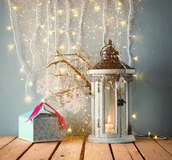 Linterna vintage de madera blanca con velas encendidas regalos de Navidad y ramas de árbol en la mesa de madera. imagen filtrada retro con superposición de brillo . —  Fotos de Stock