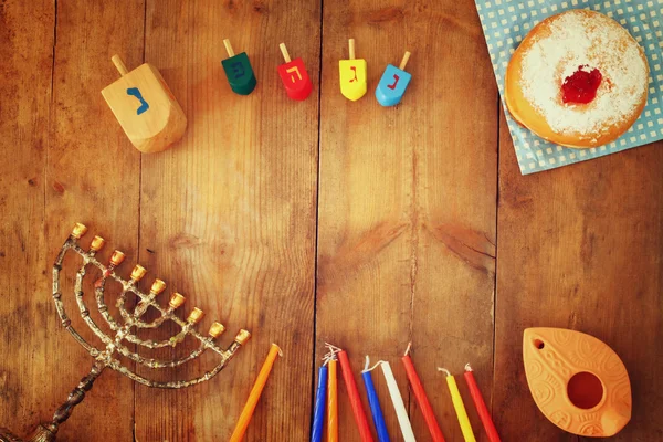 Top view image of jewish holiday Hanukkah with menorah (traditional Candelabra), donuts and wooden dreidels (spinning top). retro filtered image. — Stock Photo, Image
