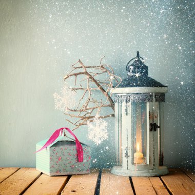 Beyaz ahşap vintage fener mum ve ağaç dalları üzerinde ahşap masa yanma ile. glitter kaplaması ile Retro filtre uygulanmış görüntü.