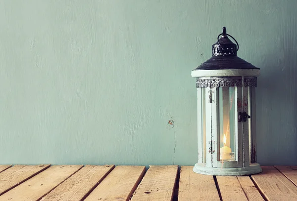 Low key image of white wooden vintage lantern with burning candle and tree branches on wooden table. retro filtered image. — Stock Photo, Image