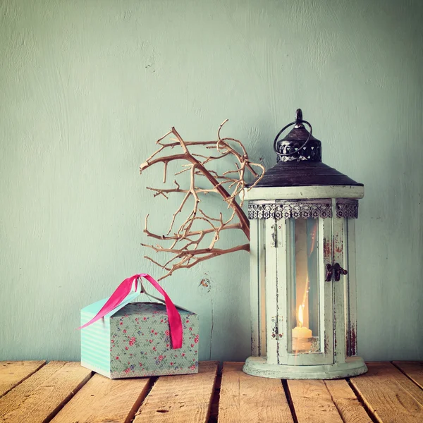 Linterna vintage de madera blanca con vela encendida y ramas de árbol sobre mesa de madera. imagen filtrada retro . — Foto de Stock