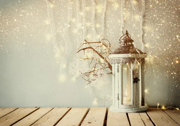 Low key white wooden vintage lantern with burning candle and tree branches on wooden table. retro filtered image. — Stockfoto