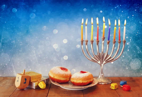 Low key image of jewish holiday Hanukkah with menorah, doughnuts and wooden dreidels (spinning top). retro filtered image. Stock Image