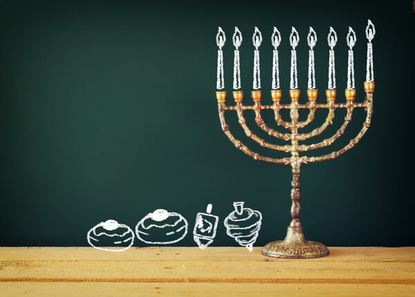 image of jewish holiday Hanukkah with drawing menorah candles (traditional Candelabra), donuts and dreidels (spinning top) over chalkboard background.
