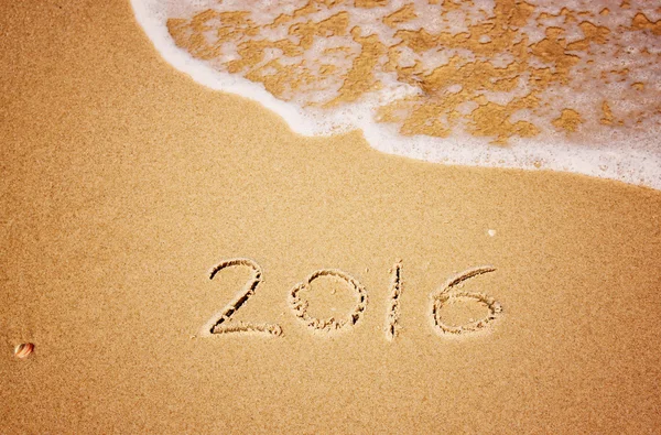 New year 2016 written in sandy beach. image is retro filtered. — Stock Photo, Image