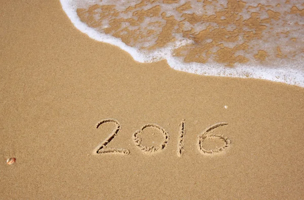 New year 2016 written in sandy beach. image is retro filtered. — Stock Photo, Image