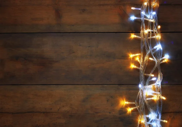 Navidad cálidas luces de guirnalda de oro sobre fondo rústico de madera. imagen filtrada . — Foto de Stock