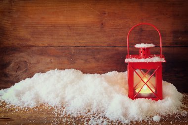 christmas background with red lantern ans snow over wooden background.