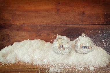 christmas background with decorations on snow over wooden background. glitter overlay.
