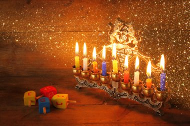 low key image of jewish holiday Hanukkah with menorah (traditional Candelabra) and wooden dreidels spinning top over chalkboard background, room for text. clipart