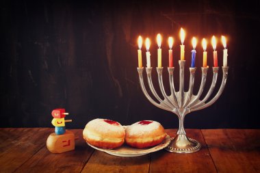 Yahudi tatil Hanukkah menorah (geleneksel Mumluk), çörek ve ahşap sevinçler (iplik üst) görüntüsü. Retro filtre uygulanmış görüntü.