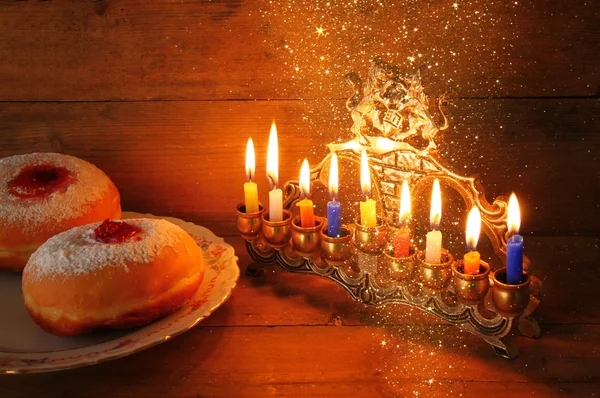 Image of jewish holiday Hanukkah with menorah (traditional Candelabra), donuts. retro filtered image with glitter overlay. — Stock Photo, Image