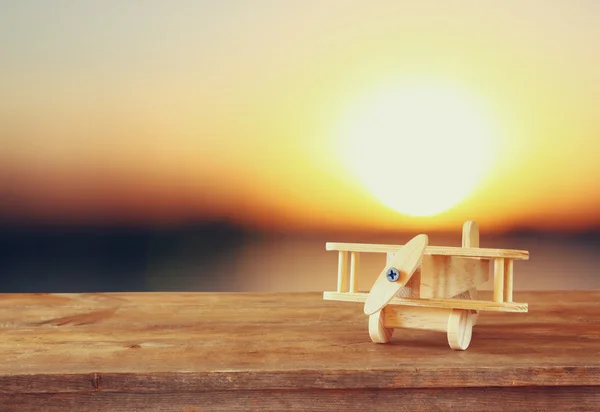 Bild eines hölzernen Spielzeugflugzeugs über einem Holztisch vor Sonnenuntergang. Bild im Retro-Stil. — Stockfoto