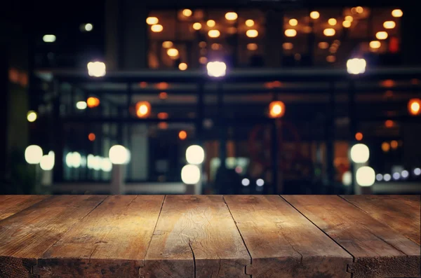 Image of wooden table in front of abstract blurred background of resturant lights. — Stock Photo, Image