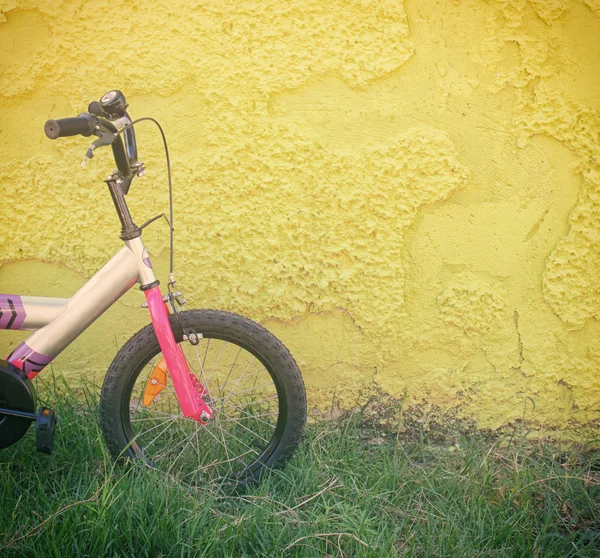 Vélo enfant à côté du mur texturé jaune . — Photo