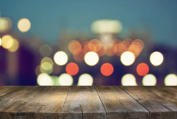 Image de la table en bois devant le fond flou abstrait des lumières de la ville . — Photo