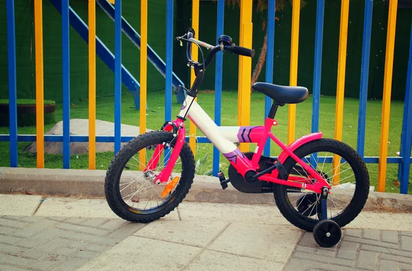 Kid fiets naast kleurrijke hek. — Stockfoto