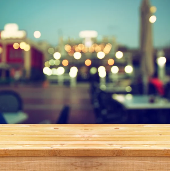 Image of wooden table in front of abstract blurred background of city lights. — Stockfoto