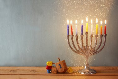low key image of jewish holiday Hanukkah with menorah (traditional Candelabra) and wooden dreidels (spinning top). glitter background.