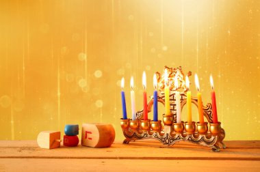 low key image of jewish holiday Hanukkah with menorah (traditional Candelabra) and wooden dreidels (spinning top). glitter background. clipart
