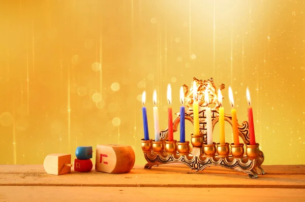 Unauffälliges Bild des jüdischen Feiertags Chanukka mit Menora (traditionellem Leuchter) und hölzernen Dreideln (Kreisel). Glitzerhintergrund. — Stockfoto