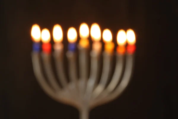 Abstracte onscherpe achtergrond van Joodse achtergrond met menora (traditionele kandelaar) brandende kaarsen op zwarte achtergrond. ⬇ Stockfoto, rechtenvrije foto door © tomert #85489622