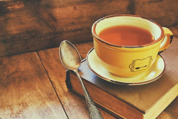 Tasse Tee mit altem Buch, Herbstblättern und einem warmen Schal auf dem Holztisch. — Stockfoto