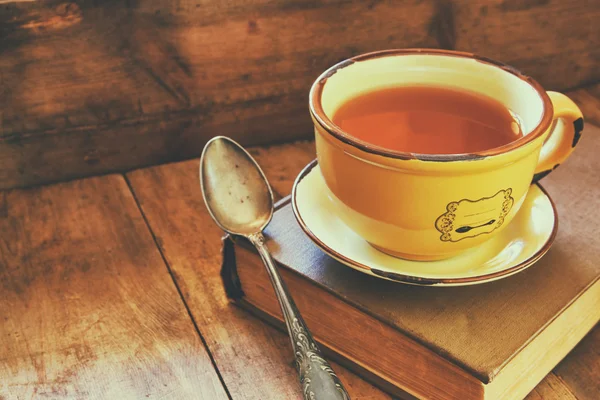 Cup of tea wit old book h autumn leaves and a warm scarf on wooden table. — Stock fotografie