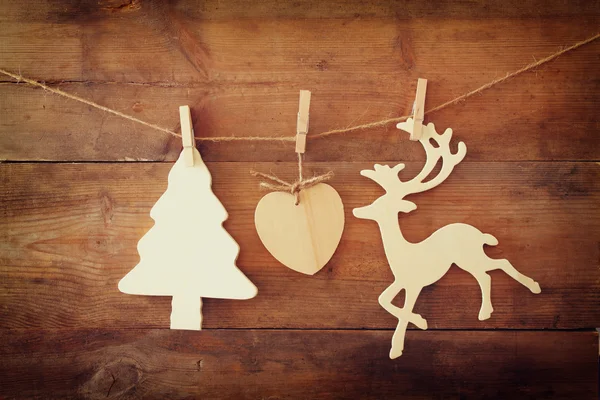 Bilden av trä dekorativa julgran och renar hänger på ett rep över trä bakgrund. — Stockfoto