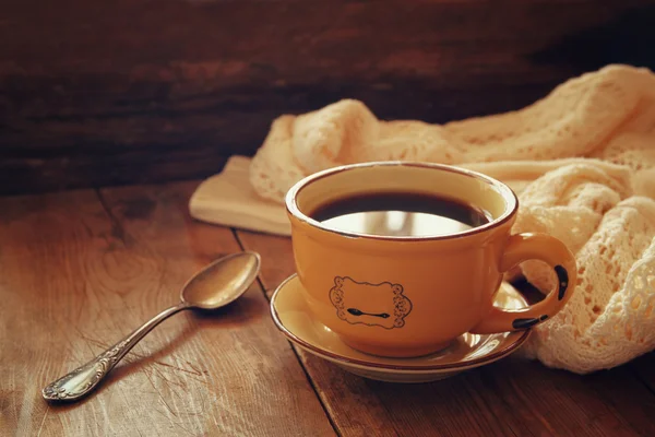 Šálek čaje se stará kniha, podzimní listí a teplá šála na dřevěný stůl. — Stock fotografie