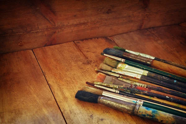 Vista dall'alto di set di pennelli usati e tavolozza su tavolo in legno. immagine filtrata retrò . — Foto Stock