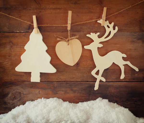 Afbeelding van de houten decoratieve kerstboom en rendieren opknoping op een touw over houten achtergrond. — Stockfoto