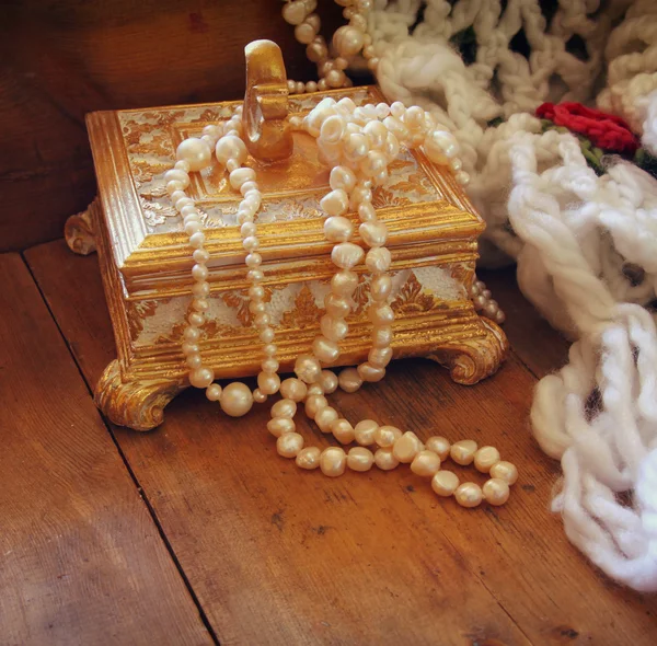 A beautiful antique golden jewelry box with natural white pearls on wooden table. — Zdjęcie stockowe