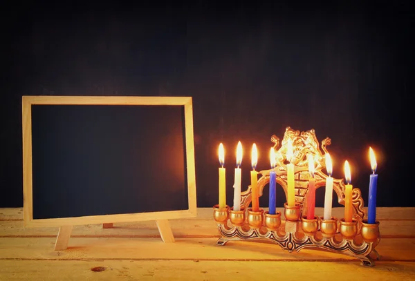 Lage sleutel imago van Joodse vakantie Hanukkah met menora (traditionele kandelaar) en houten schoolbord, ruimte voor tekst. — Stockfoto