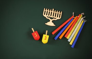 image of jewish holiday Hanukkah with wooden decorative menorah (traditional Candelabra) and wooden dreidels spinning top over chalkboard background, room for text.